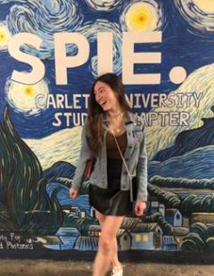 student standing in front of a background that reads SPIE Carleton University.