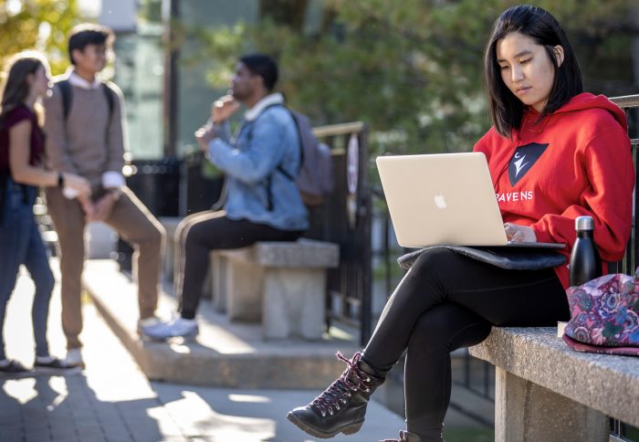 A student sits with a laptop in Carleton's quad.