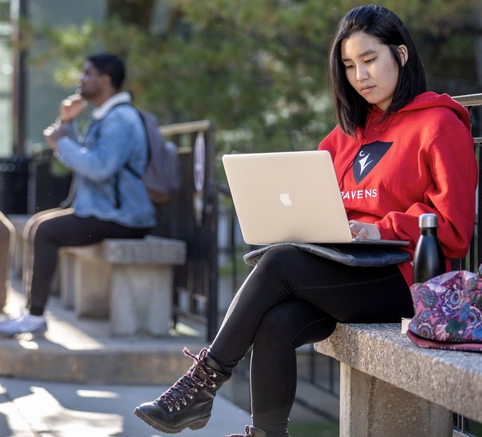 A student sits with a laptop in Carleton's quad.