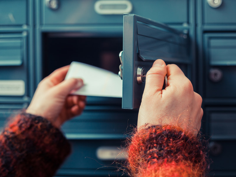 A woman checks a physical mailbox