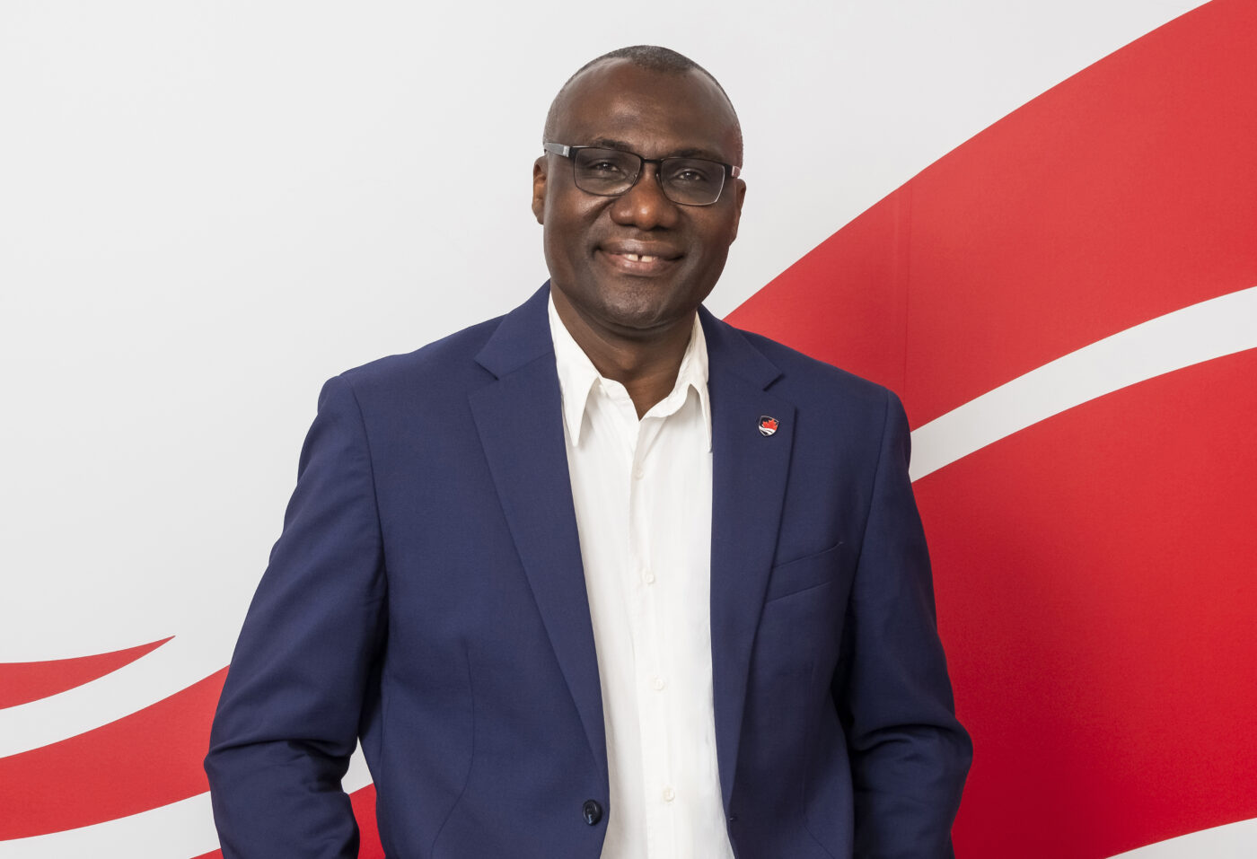 President Wisdom Tettey standing in front of Carleton wave imagery