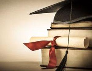 cap and tassle on pile of books with diploma scroll