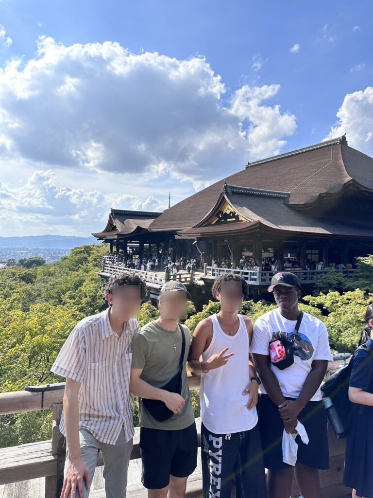 Julian and friends (with blurred faces) standing in front of a pagoda.