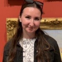 Madison in an art gallery. Picture frames hang behind her.