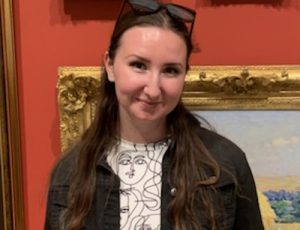 Madison in an art gallery. Picture frames hang behind her.