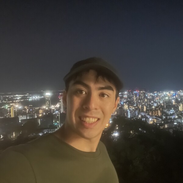 Rui at night with city lights behind him