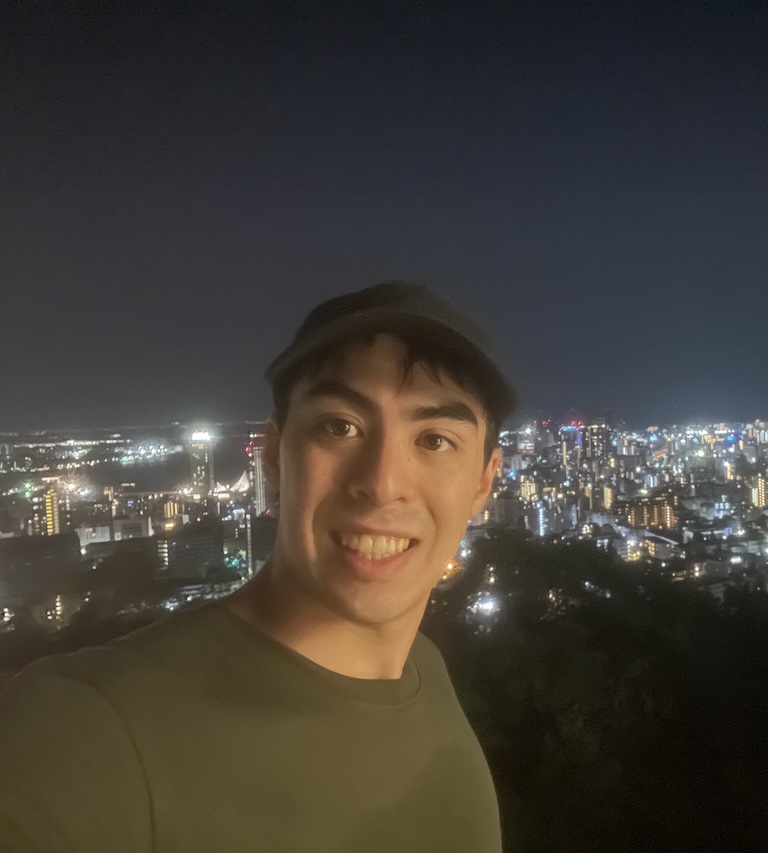 Rui at night with city lights behind him