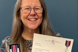 Denise smiling as she shows the award