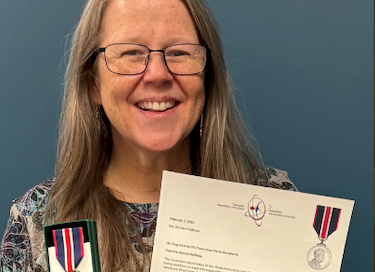 Denise smiling as she shows the award