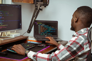 Man seated at a desk writing code.
