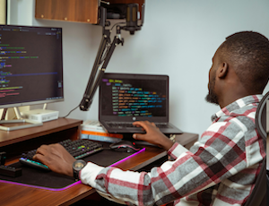 Man seated at a desk writing code.