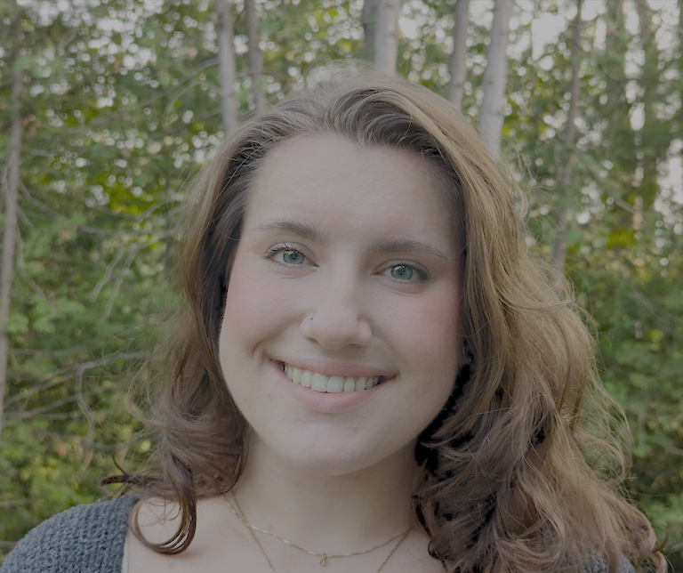 Cora smiles at the camera while out in nature