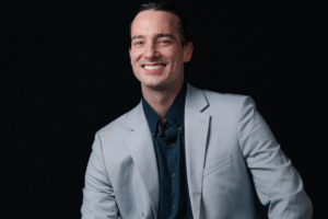 Dallas sitting comfortably in a suit with his hands on his knees