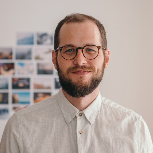 Adam standing in front of a wall of photos