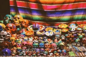 Day of the Dead altar showing brightly coloured blanket and large pile of painted skulls