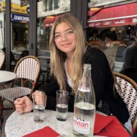 Josefina sitting at a cafe. Glasses of Evian water are on the table.