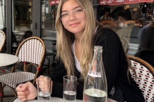 Josefina sitting at a cafe. Glasses of Evian water are on the table.