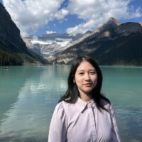 Maggie in front of Lake Louise with mountains and blue skies.