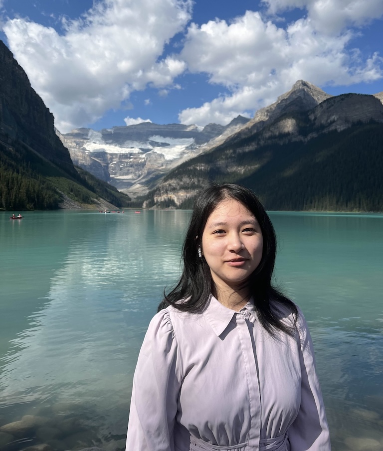 Maggie in front of Lake Louise with mountains and blue skies.