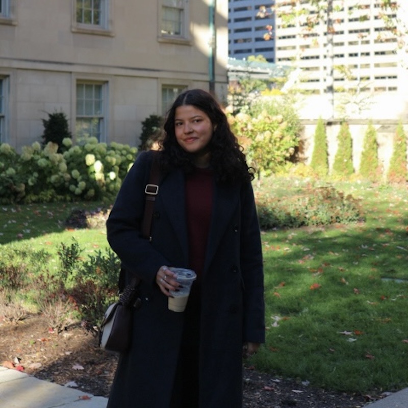 Andrea standing in a garden with a cup of coffee