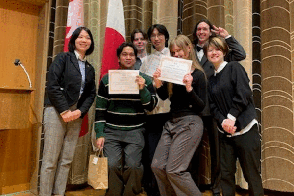Group of contestants and instructors in front of Canadian and Japanese flags