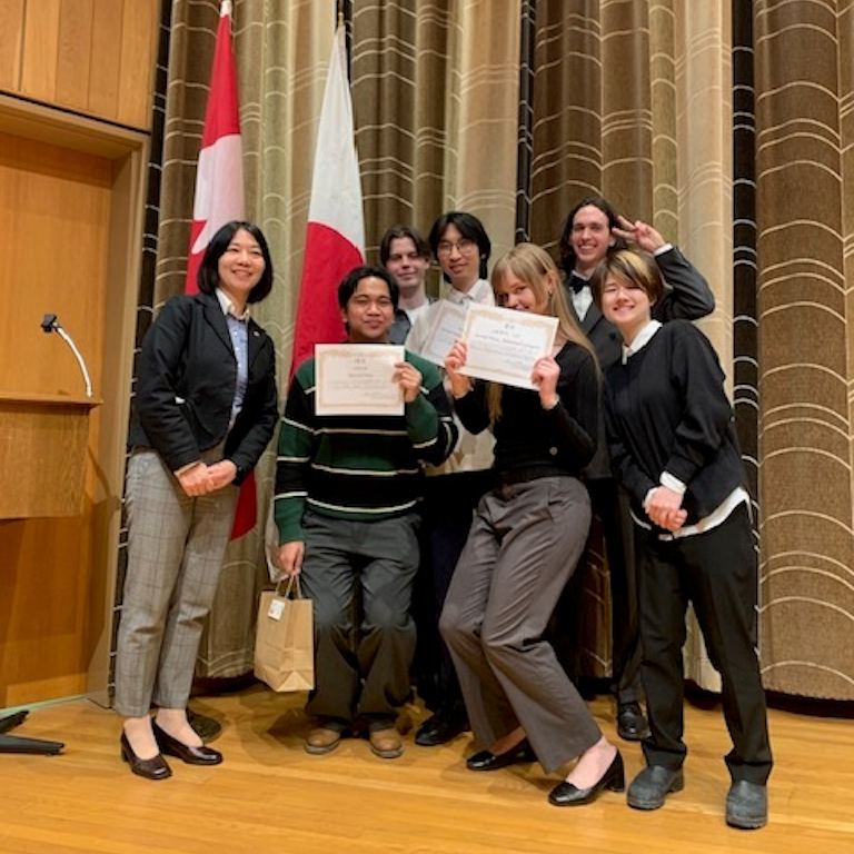 Group of contestants and instructors in front of Canadian and Japanese flags