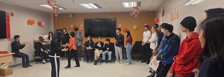 Group of students gathered around the wall.  Max is doing a wall-sit.