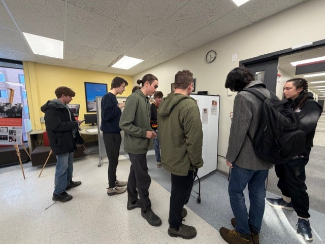 Group of students mingle around poster presentation