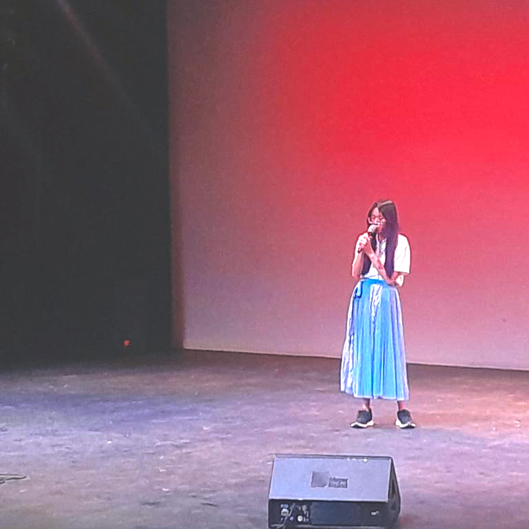 Chau singing against a red background