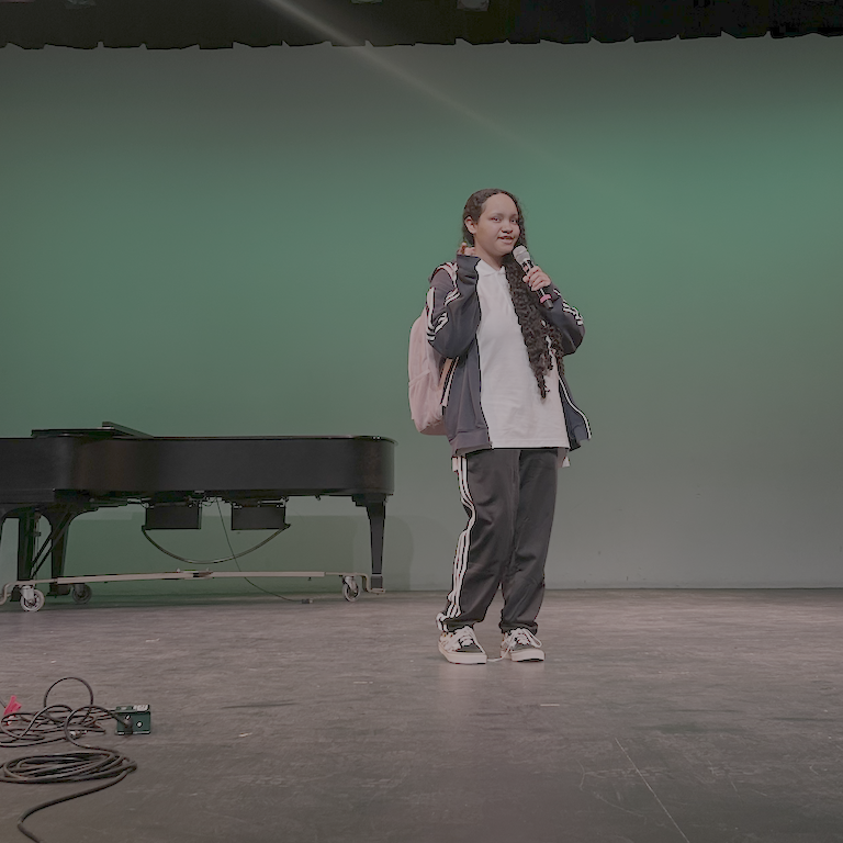 Nöela in a track suit and backpack (just like the video) looks coyly at the camera.