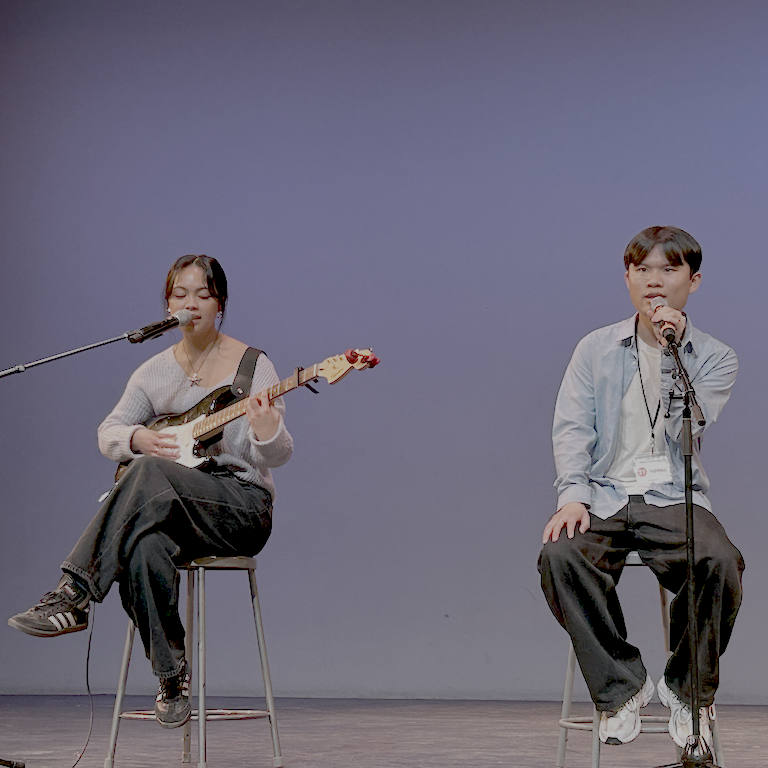 Keisha seated left plays an electric guitar and sings opposite Viphop.