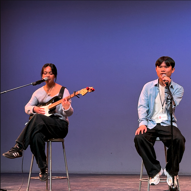 Keisha seated left plays an electric guitar and sings opposite Viphop.
