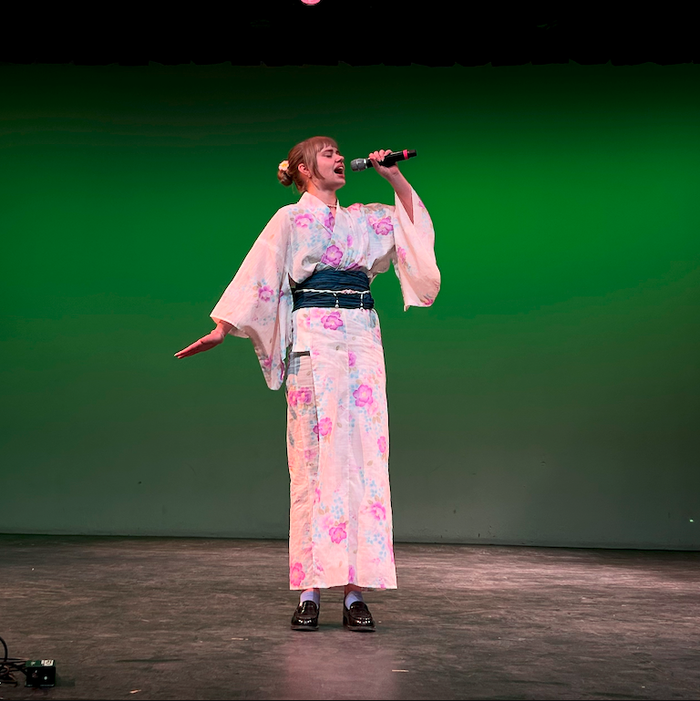 Serena dressed in a pink flower kimono belts out  her song.