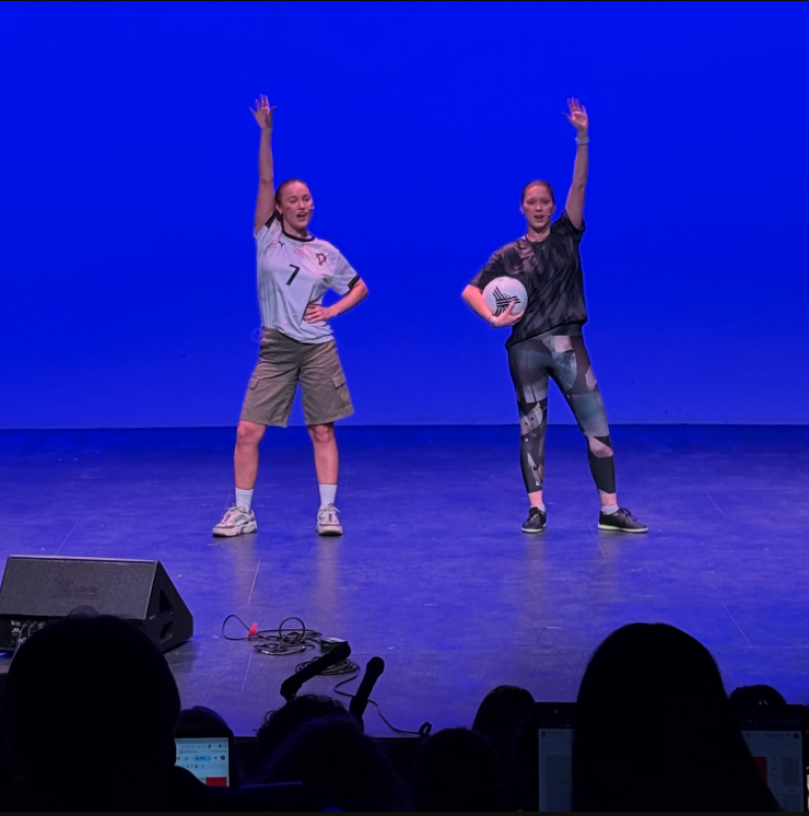 Stef and Alex at the end of their performance, hands raised, soccer ball in hand.