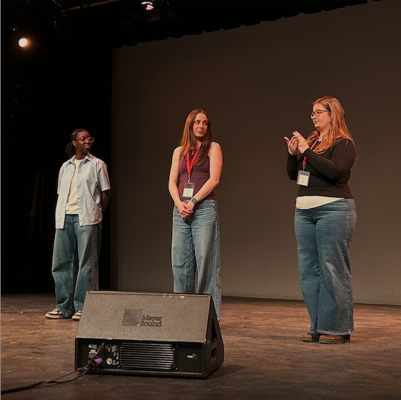 Three students signing to each other on a stage.