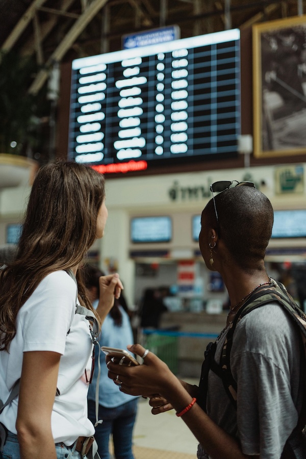 Two women look at airport departure board.