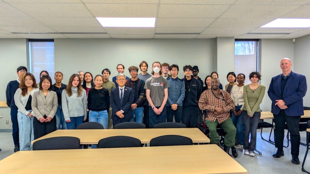 Students, instructors and Ambassador standing at the front of the room.
