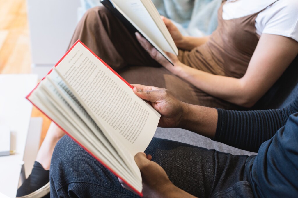 Two people sitting next to each other reading