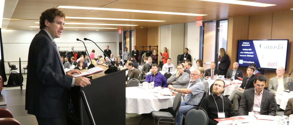 A middle-aged white man addresses a packed conference session