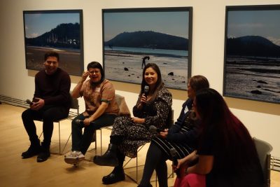 Four participants sitting in chairs in front of art at the Carleton Art Gallery