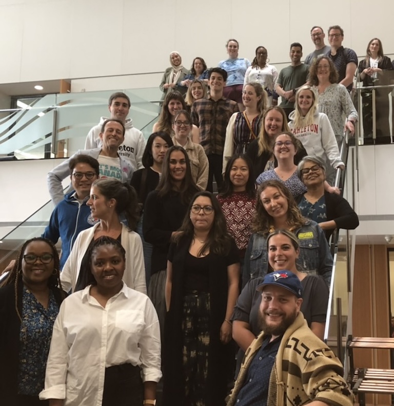 The 2025 cohort of students stands in a stairwell and smiles at the camera.