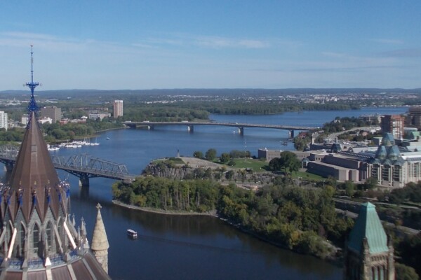 An aerial view from the top of Peace Tower at Parliament Hill, in Ottawa, with a panorama of the horizon, trees and two, long bridges crossing the Ottawa River.