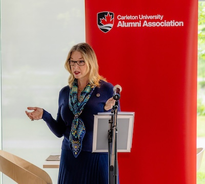 Rebecca Murray speaks at a microphone about the newly launched MPNL Alumni Association.
