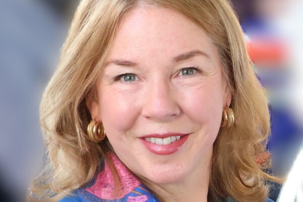 A woman, Rebecca Murray, wears a scarf and earrings and smiles at the camera.