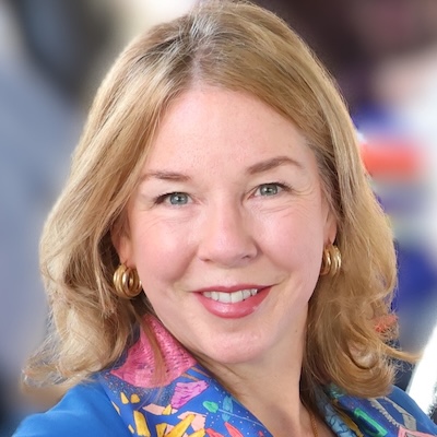 A woman, Rebecca Murray, with earrings and long hair smiles at the camera.