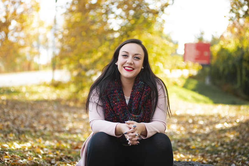 Image of Kaitlan Brazeau sitting outdoors with fall leaves in the background