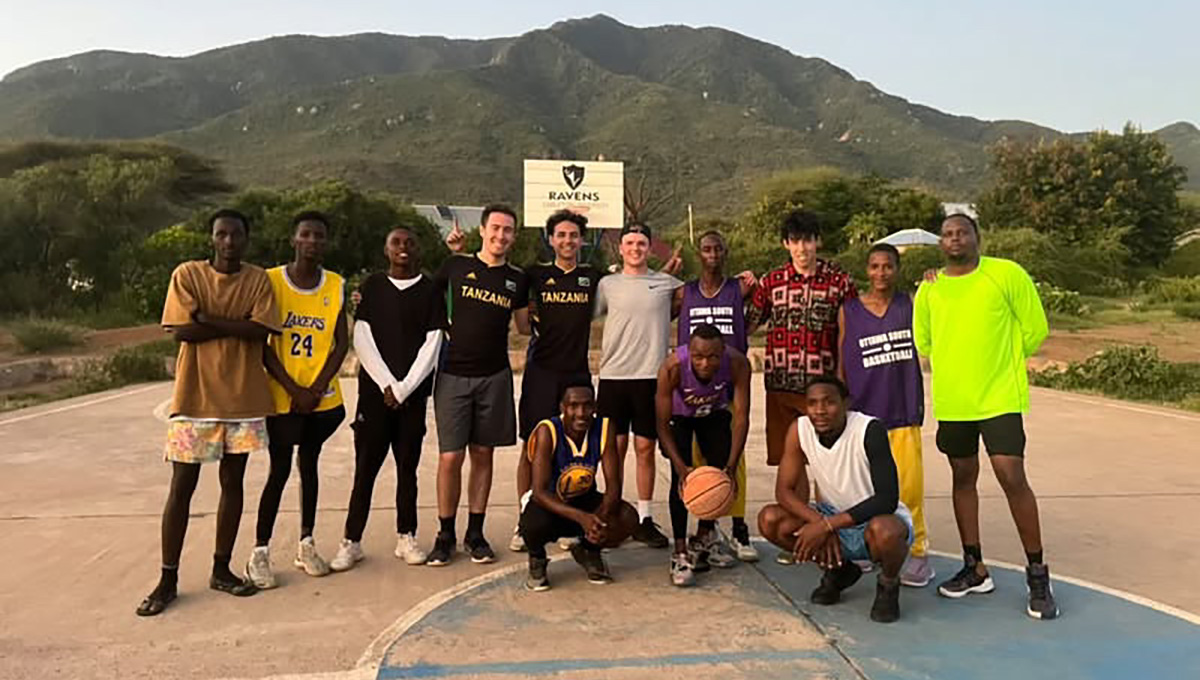 A group of young people posing for a photo on an outdoor basketball court.