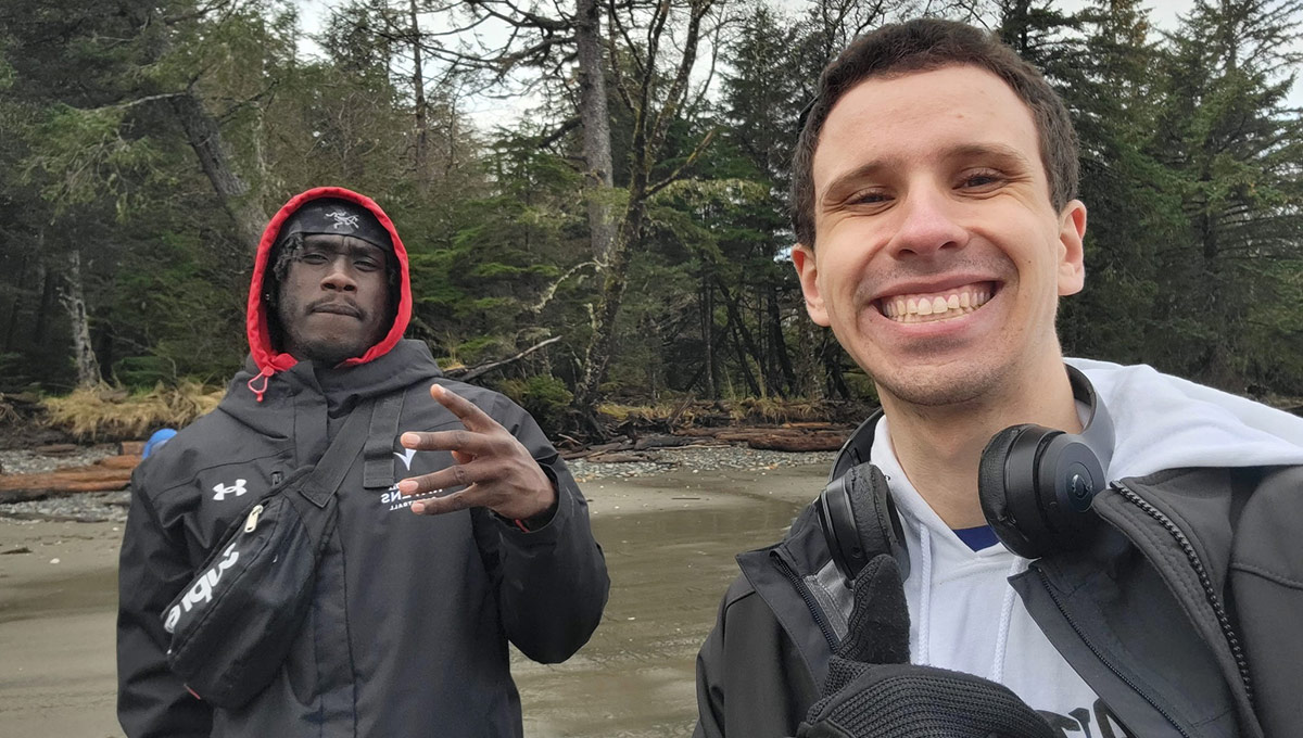 Two people posing for a photo by the bank of a river while helping remote communities.