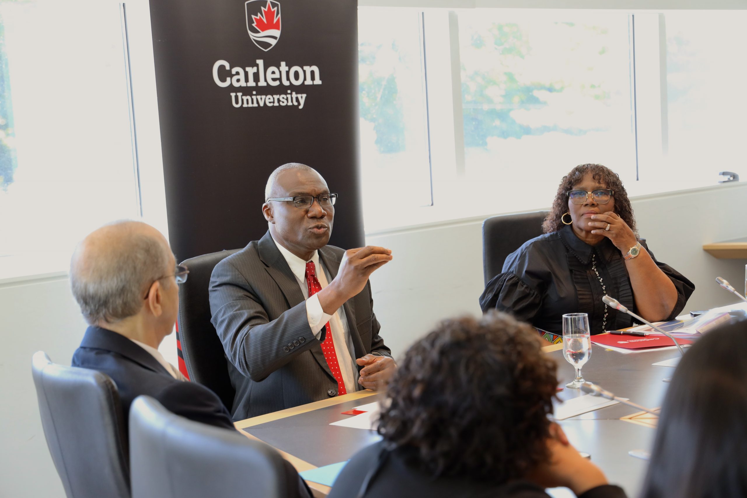 Wisdom Tettey talking at MOU signing while sitting at a table