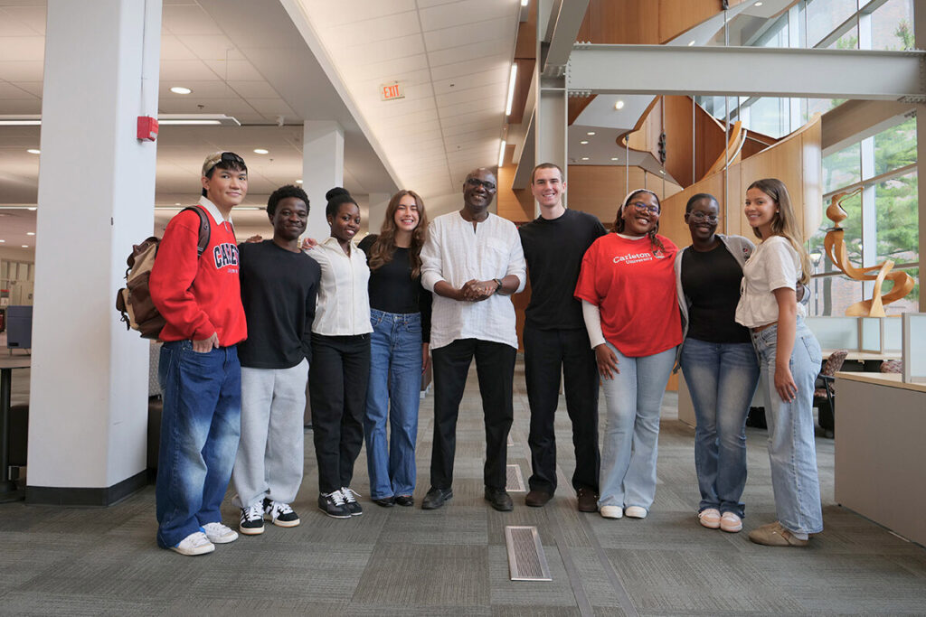 A large group of people posing for a photo next to an art display, inside a building.